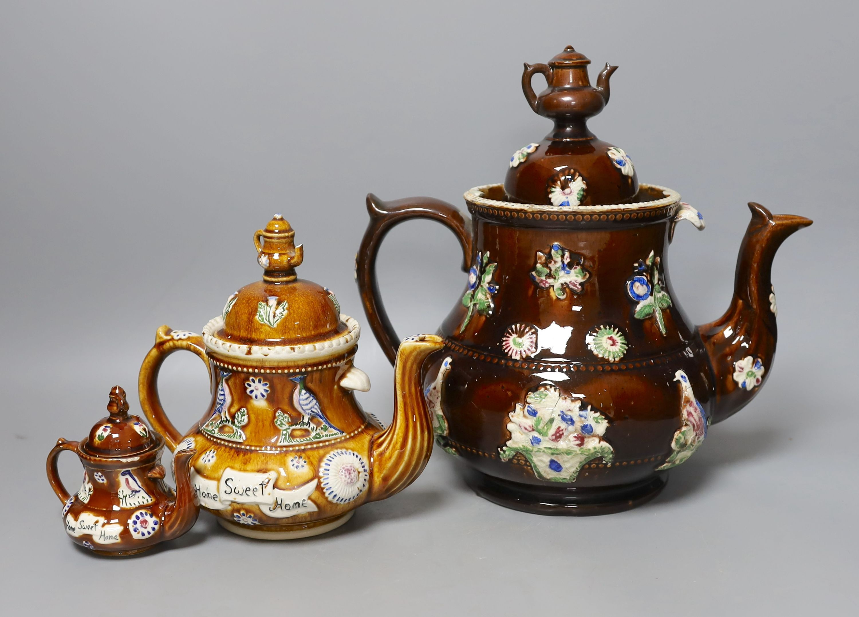 A Victorian Measham Bargeware pottery tea pot and cover, 29cm high and two similar reproduction teapots
